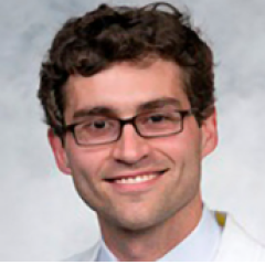 Close up of a man wearing glasses and white lab coat smiling.