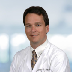 Headshot of a smiling man in white lab coat and tie.
