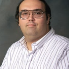 Man in white striped shirt and glasses, headshot.