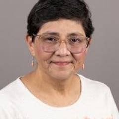 Photo of a woman with short black hair wearing glasses and a white blouse.