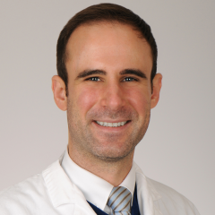 Smiling man in white lab coat and striped tie.