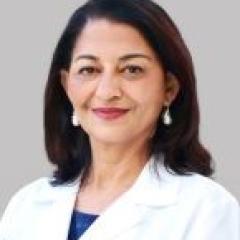 Portrait of a smiling woman in a white lab coat with blue earrings.