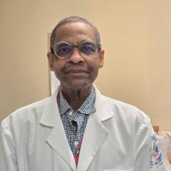 Portrait of a man in a white lab coat and glasses.