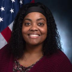 Portrait of a woman smiling in front of an American flag.