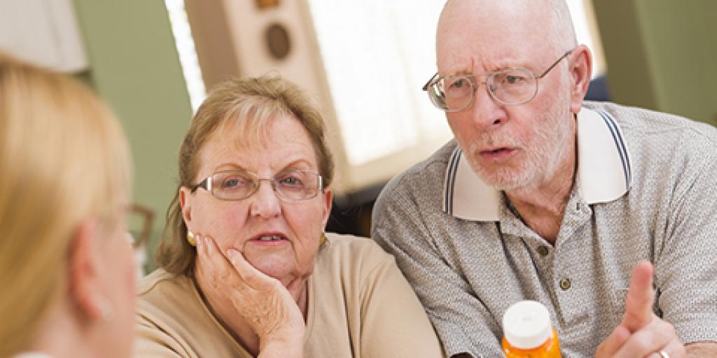 Pharmacist explaining prescription medicine to attentive senior couple