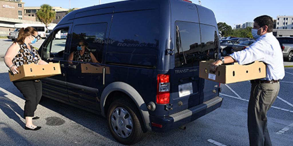 Charleston VAMC Director Scott Isaacks and High Reliability Program Manager Kathleen Gillard load boxes of fresh produce into a Veteran's van. Photo by James Arrowood.