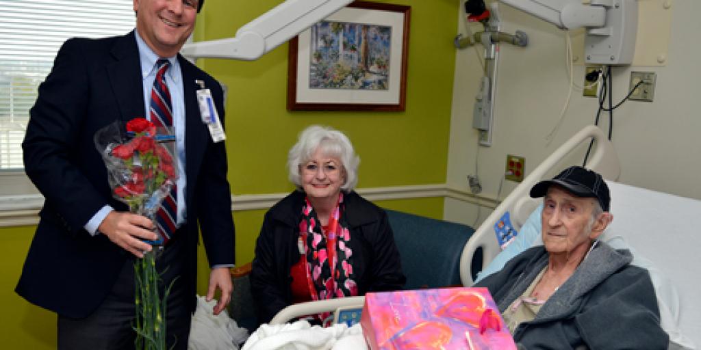 Charleston VAMC Director and CEO Scott Isaacks visits Veteran Michael Scarbourgh and his wife to deliver carnations and well wishes during National Salute to Veteran Patients Week.