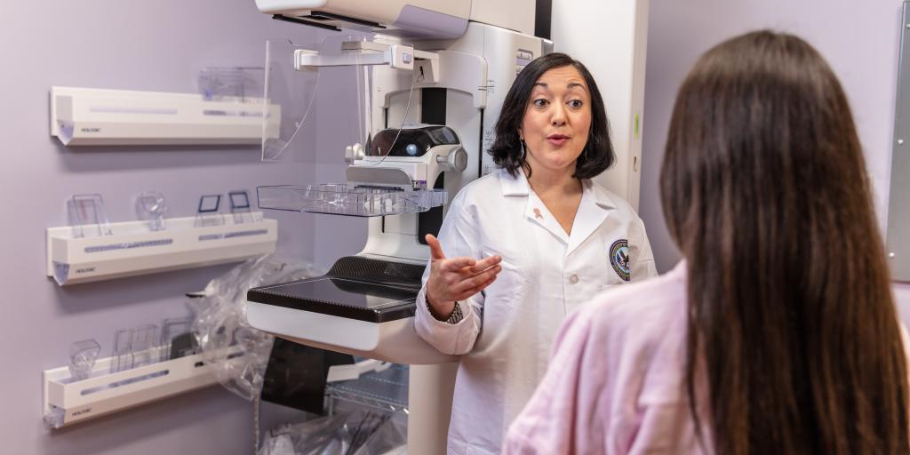 Doctor and patient standing by a mammography machine.