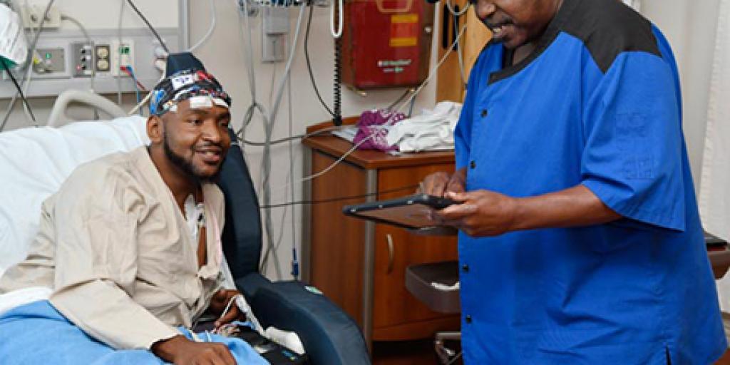 Nutrition and Food Service employee Broderick Belton helps Veteran Douglas Kyle select his inpatient meal through the use of an iPad. Photo by Brandy Sims. 