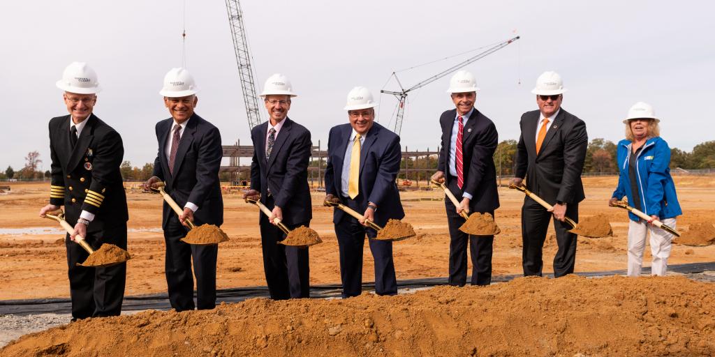 Leaders from many state, local and federal government entities lift shovels full of dirt at a groundbreaking ceremony