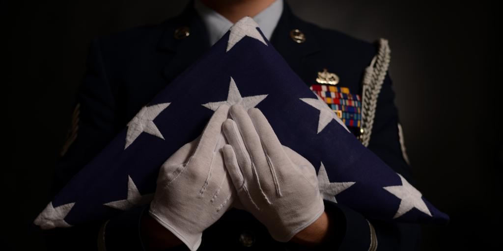 Military member presenting a folded U.S. flag
