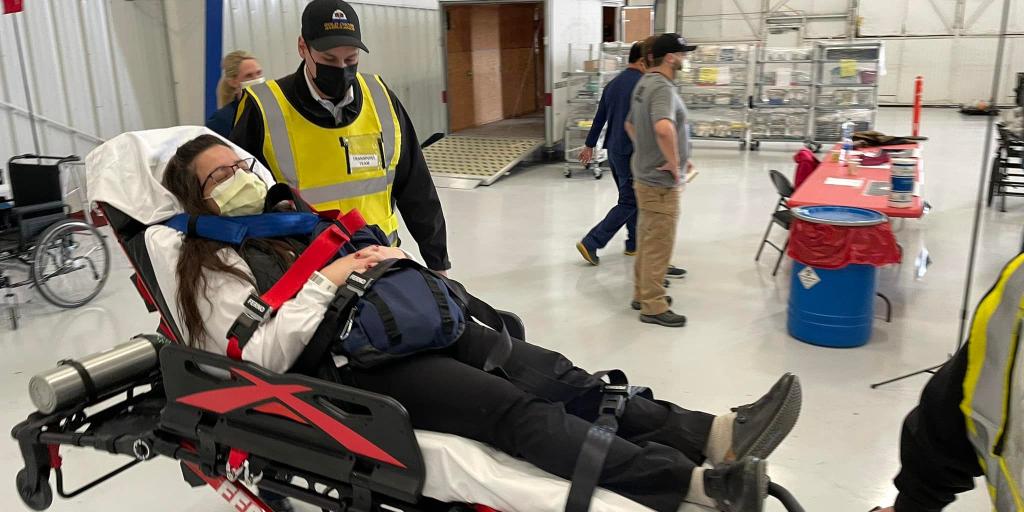 An emergency responder attends to a patient on a gurney during a preparedness exercise