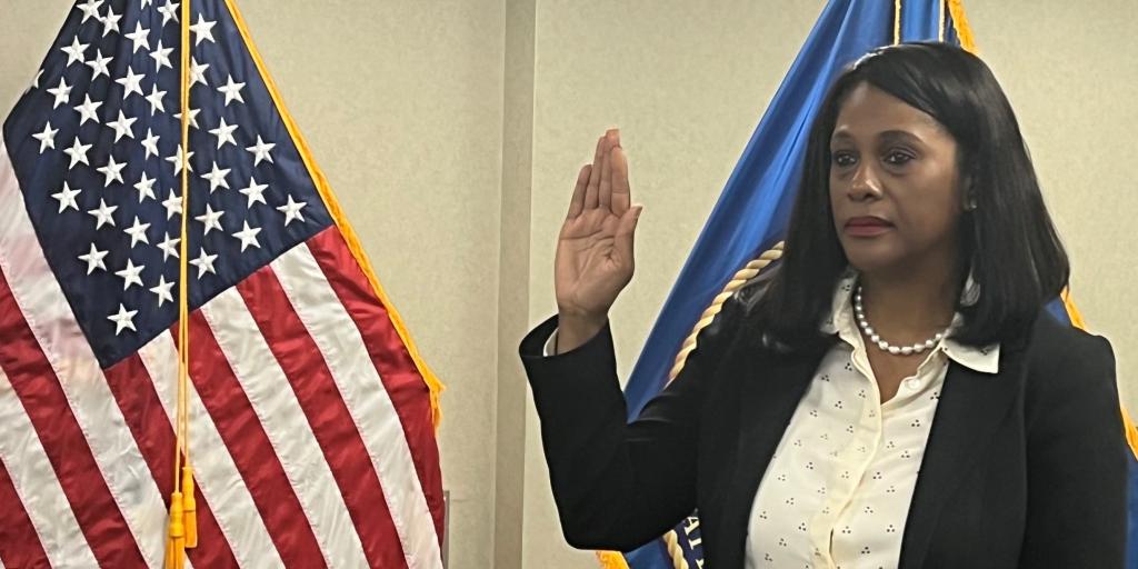 United States flag on left with woman on right with right hand raised