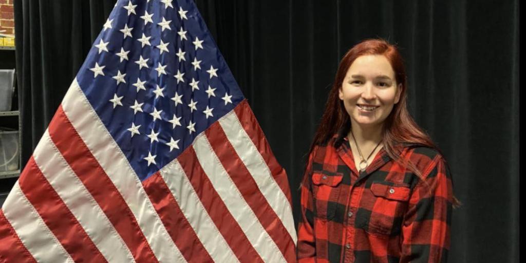 Navy Veteran Chelsea Snoey standing next to the American flag.