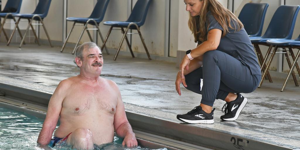Physical therapy assistant works with VA patient in a pool