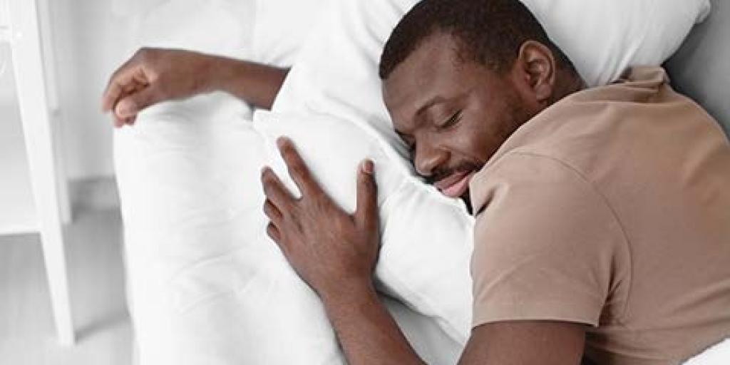 A man is sleeping and hugging his pillow