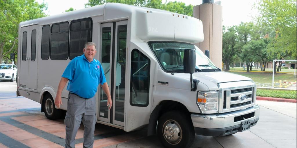 Shuttle driver stands in front of shuttle bus