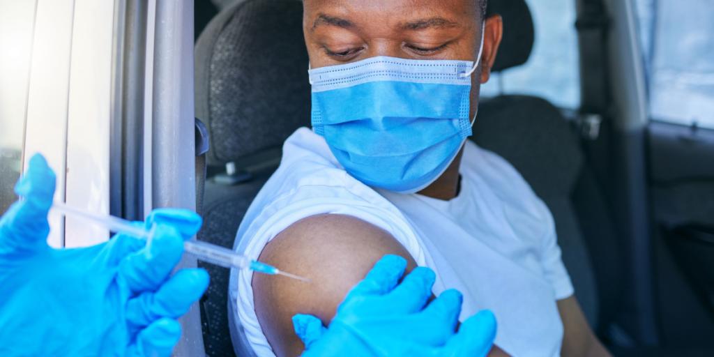 A man receives a vaccination in a drive-thru clinic