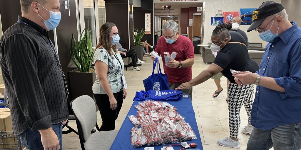 Man stands next to table covered in blue cloth to look at gun locks at the Nashville VA on Firearm Safety Day.