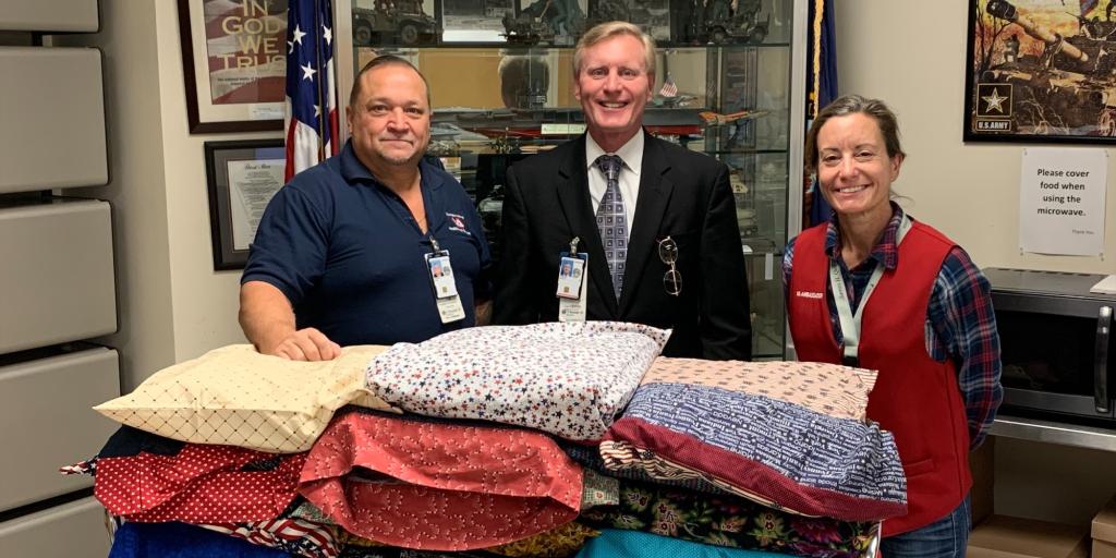 MOUNTAIN HOME, TN — Voluntary Services at James H. Quillen VA Medical Center (JHQVAMC) and Quilts of Valor Foundation partnered Dec. 8, 2022, providing hand-made quilts to in-patient residents at the medical center during the holiday season. Pictured from left to right are Mike Kromoff, the chief of Voluntary Services at JHQVAMC, Medical Center Director Dean B. Borsos, and Sarah Smith, a red-coat ambassador at JHQVAMC. (Photo: James H. Quillen VA Medical Center)