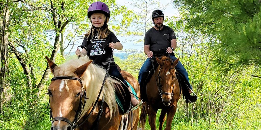 grandfather and granddaughter riding horses together