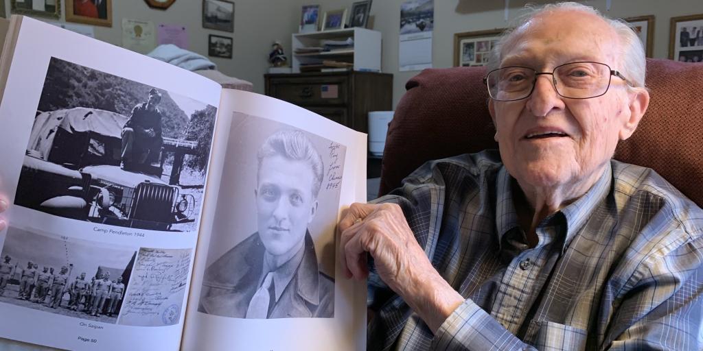 Leroy Stoehr holding up a photo of himself from 1945.