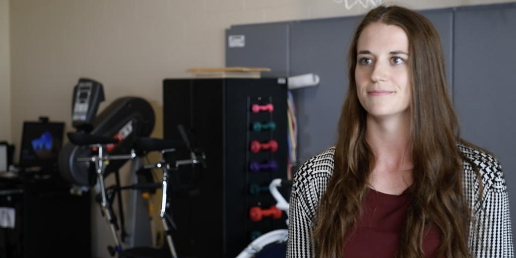 photo of a person with long brown hair standing in front of adaptive sports equipment