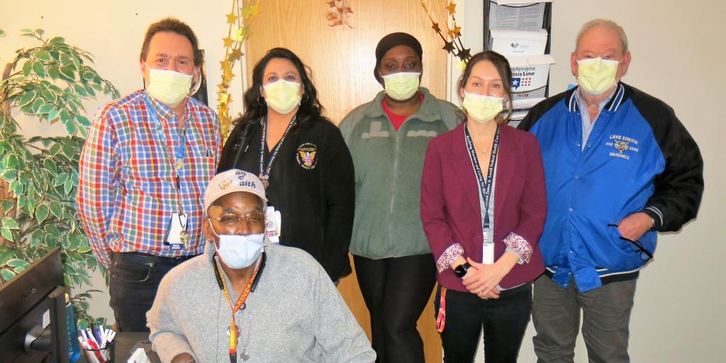 Veterans and the social workers who helped them find Permanent Housing Placements in 2022 pose in the Walk-in Center for Homeless Veterans at Lovell Federal Health Care Center