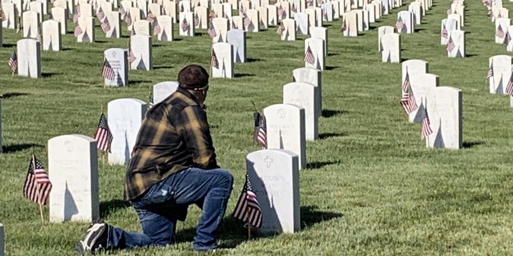 Veteran kneels before tombstone