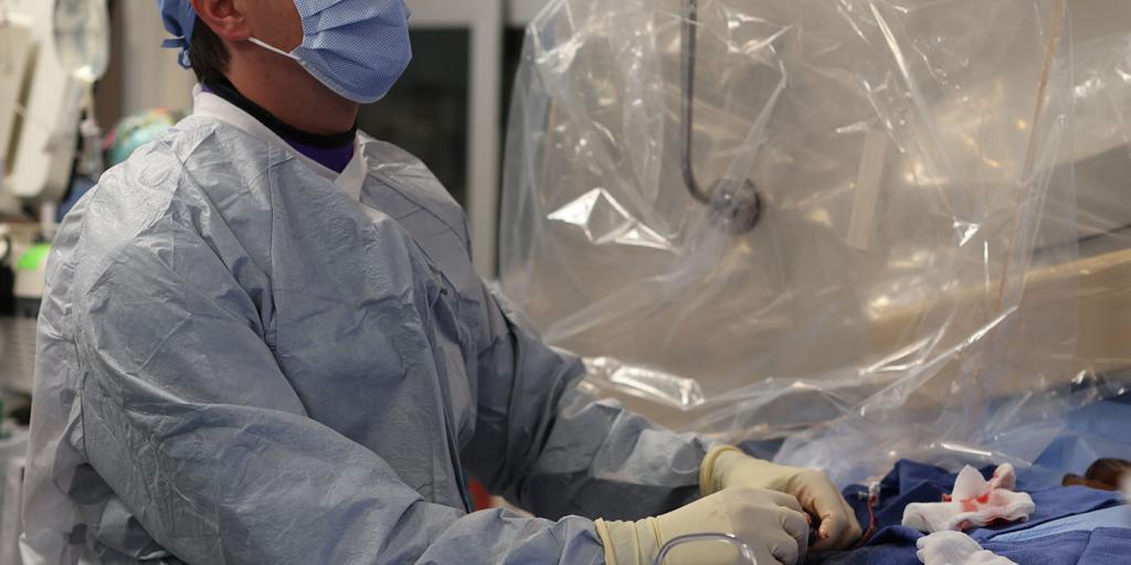 A surgeon looks at a monitor to check vitals during a heart procedure