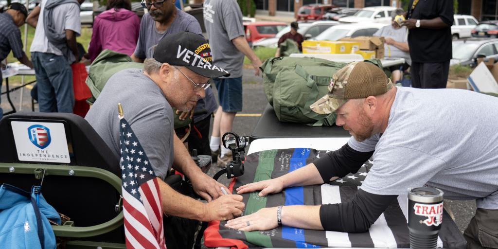 A Veteran signs a flag during a Veteran Stand Down.