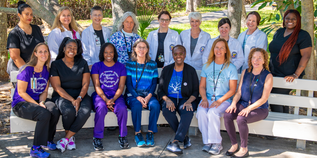 A group of female health care professionals gather outside on a sunny day for a group photo