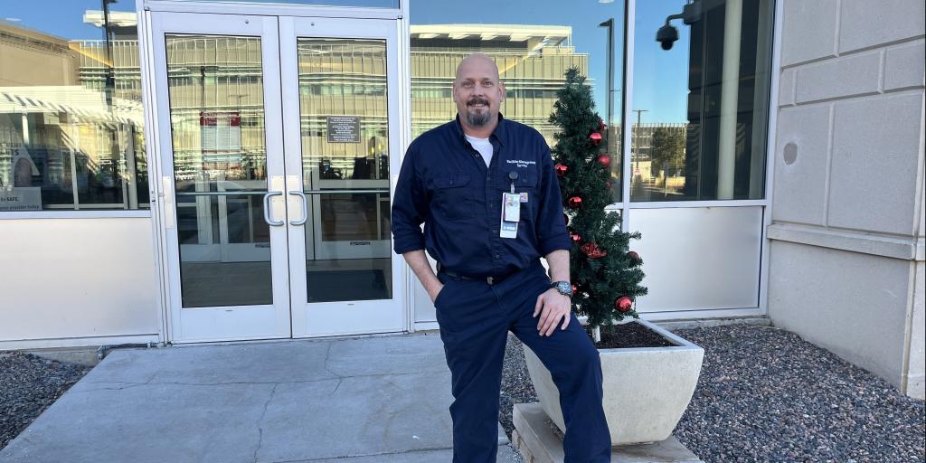 Man standing outside VA in dark uniform from his department.