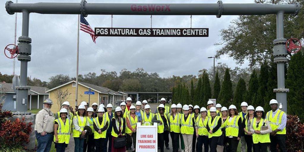 A group of people stand outside under an awning at TECO Peoples Gas training facility.