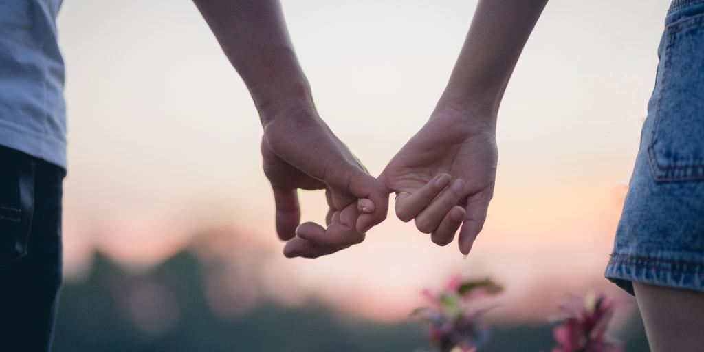 Close up of a couples' hands with small fingers interlocked.