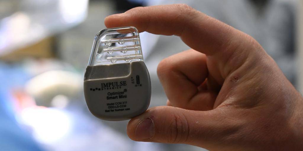 Hand holding a CMM device while a medical procedure takes place in the background