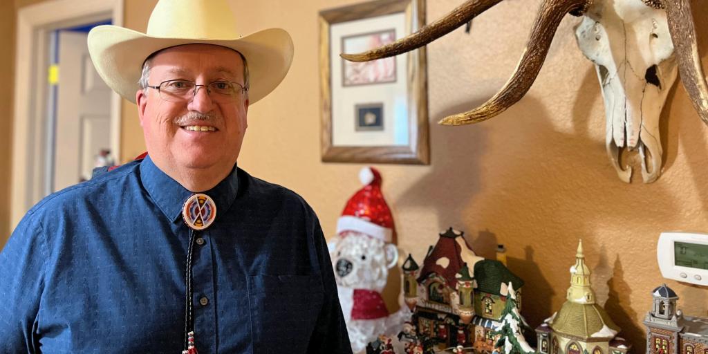 Army Veteran John Lawton in a cowboy hat, blue dress shirt and necklace.