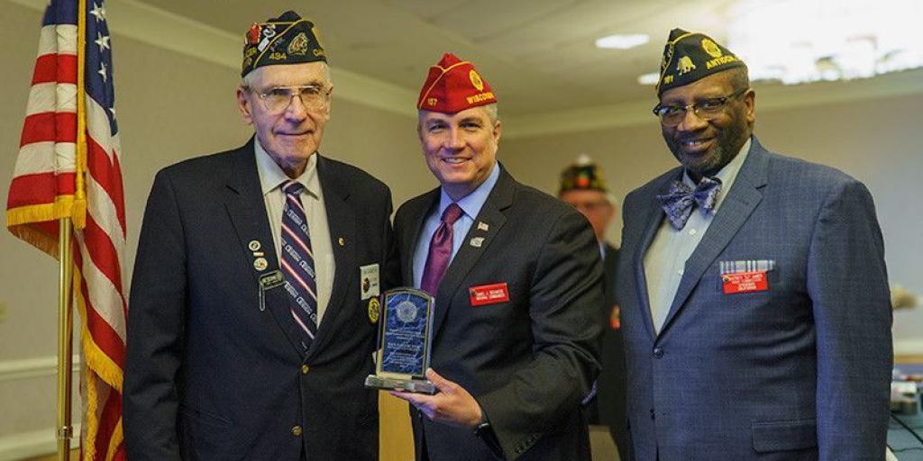 Three men hold plaque for American Legion award.