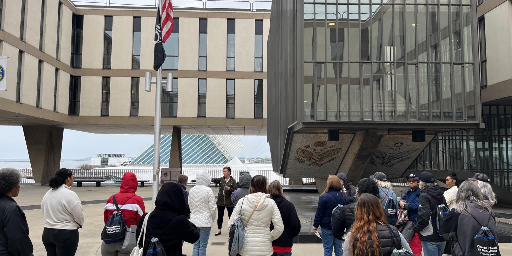 A group of female Veterans stand near a flag and the eternal flame monument at the Milwaukee County War Memorial Center
