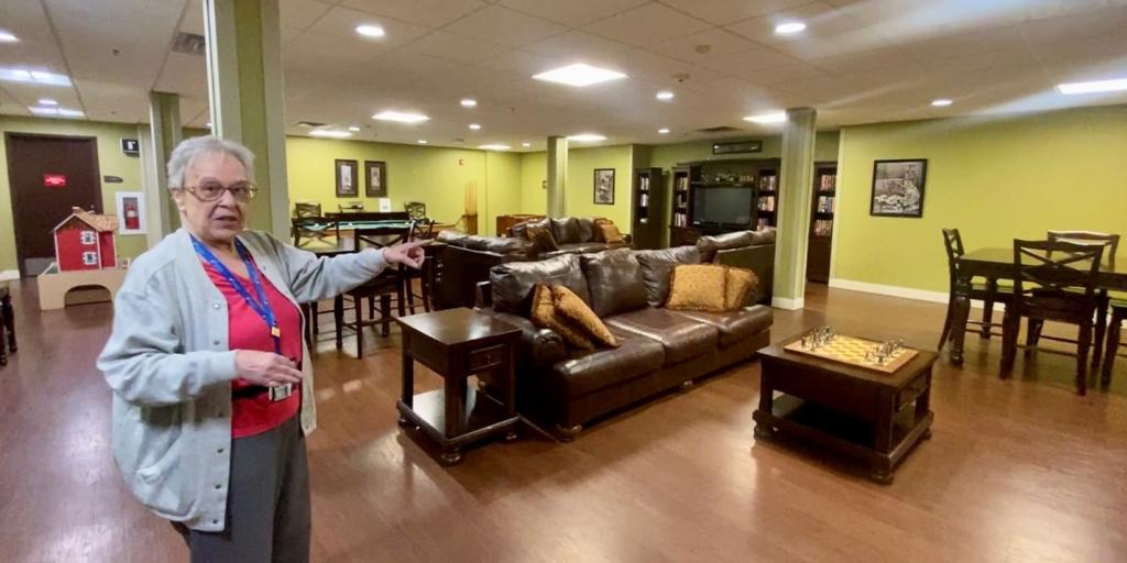 Women standing in large room with hand outstretched showing features of room