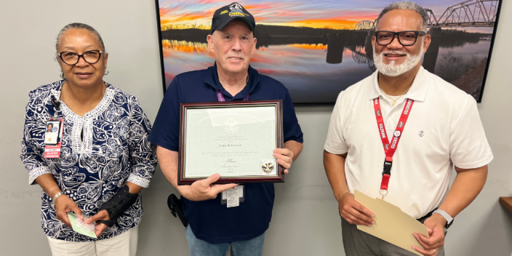 Gary Suddeath, a Navy Veteran and Clarksville VA volunteer, smiles with his President's Lifetime Volunteer Award with two VA employees next to him.