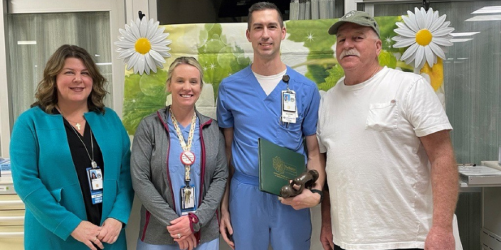 A group of nurses and a patient smile for a group photo.