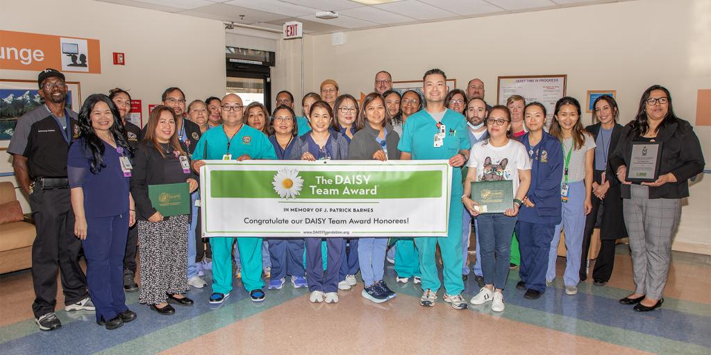 Community Living Center Hospice Team, roughly 30 employees posing with the DAISY Team Award banner