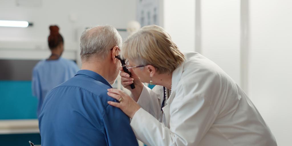 Audiologist inspecting patients ear.