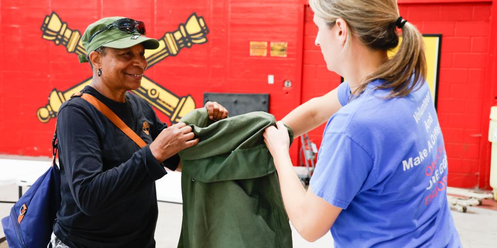 Veteran holds bag while volunteer places item inside
