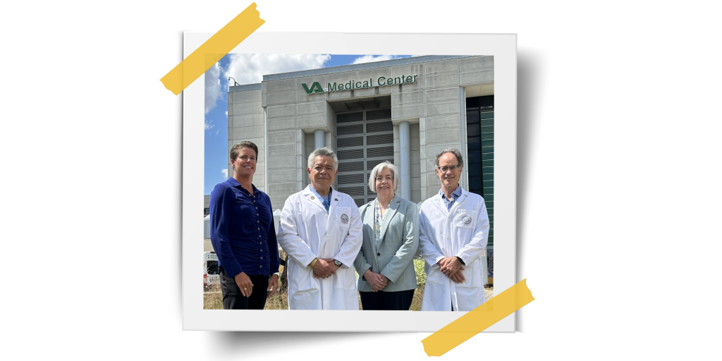 group of 4 people standing in front of a grey and green building that says VA Medical Center