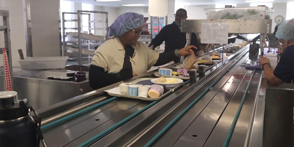 People in a line placing food on trays.