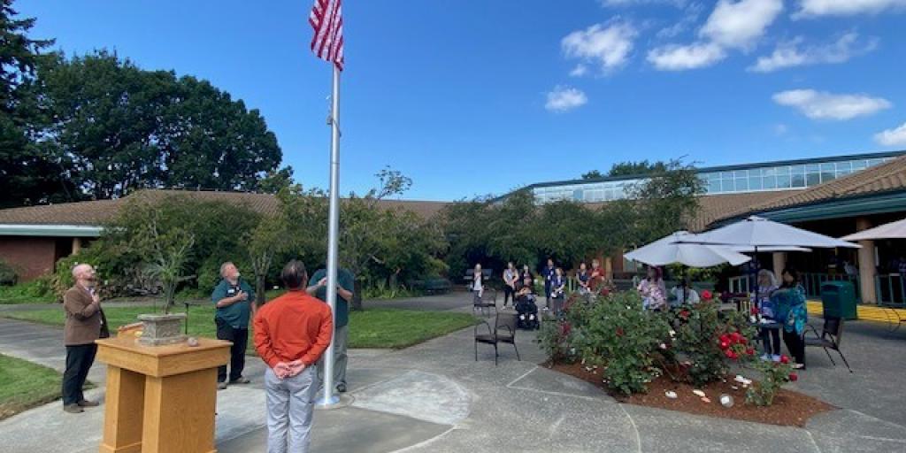 Attendees at Flagpole dedication ceremony looking on as US Flag is raised on the new pole for the first time.
