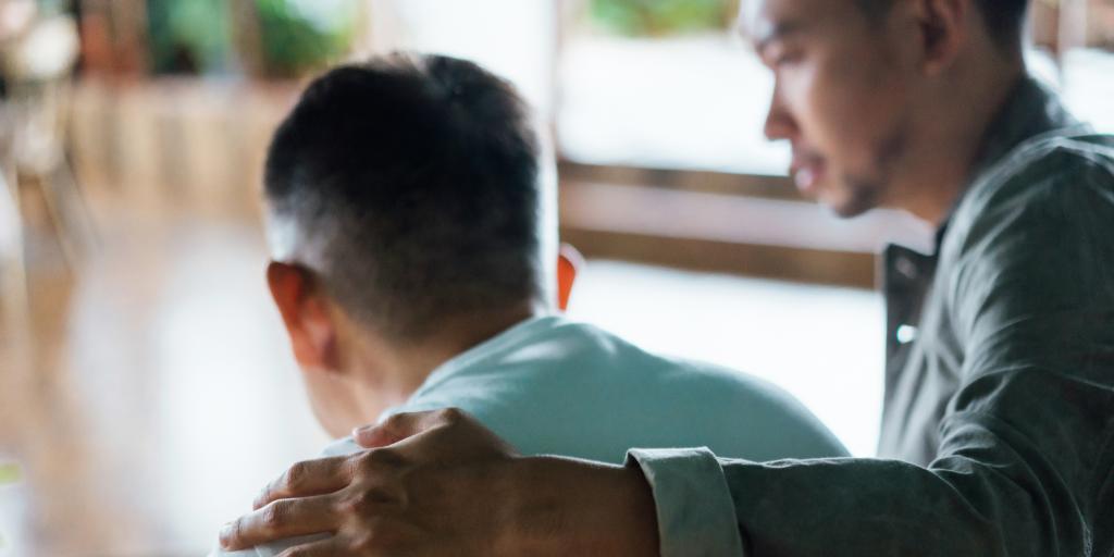 Man with hand on back of another man