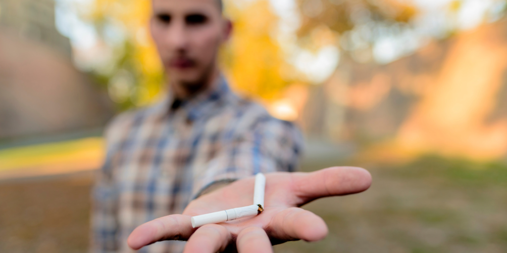A man holds a broken cigarette in his hand, reflecting the moment he quit smoking.